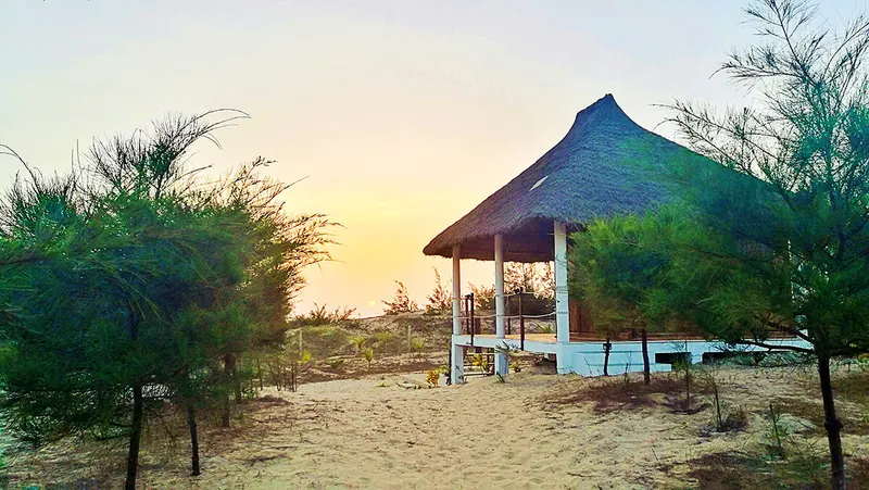 Case de chaume au coucher du soleil, au bout d'un chemin de sable à Cap Skirring