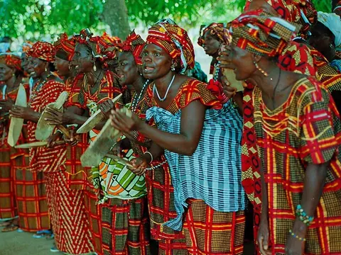 Femmes diolas en tenues colorées chantant et dansant lors d'une soirée culturelle